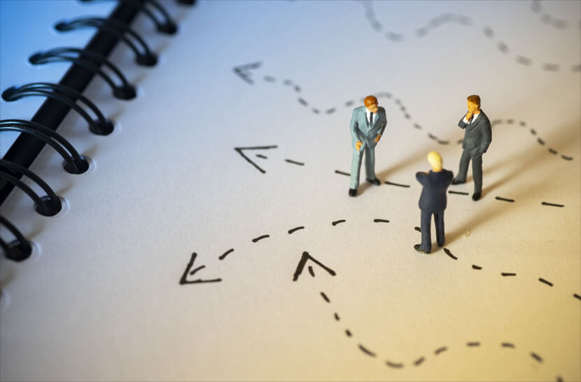 businessmen standing over arrows-pointing in different directions